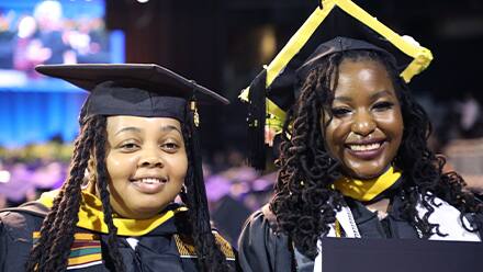 Diane Sanda, left, and Samiyah Muhammed, right, dressed in their SNHU graduation cap and gown.