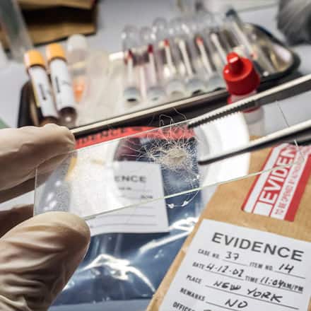A crime scene investigator handling evidence in a laboratory.