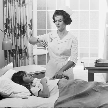 Split image of a black and white photo of a nurse helping a sick patient laying in a bed on one side and a colored image of a nurse speaking to a child patient and her mother on the other.