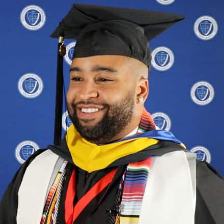 SNHU graduate Luis Polanco smiling and wearing his graduation cap and gown.
