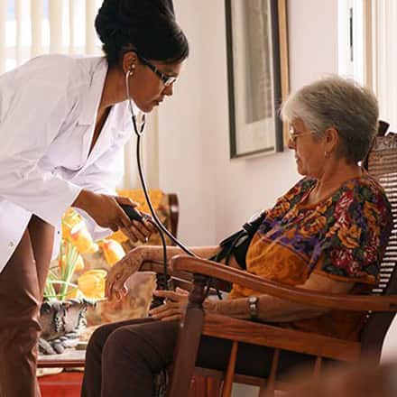 A healthcare professional checking the blood pressure of a woman in an assisted living facility.