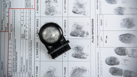 A fingerprint form with a magnifying glass.
