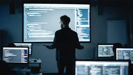 A person with a master's in computer science reviewing code on a big screen for his job