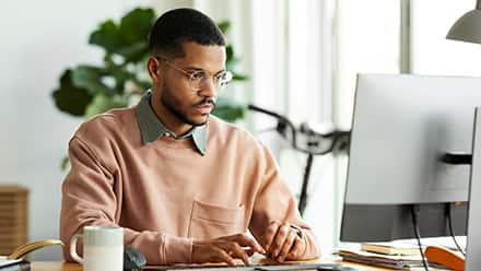 A man working on his desktop researching the types of graduate degrees