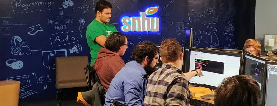 A group of students looking at a computer screen at SNHU's game design studio