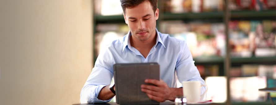 Student sitting at a table using a tablet to check his professional social networking profiles