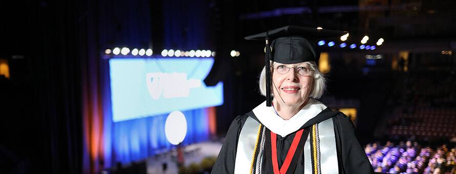 SNHU graduate and Ohio resident Mary Carbone wearing her cap and gown at commencement in the SNHU Arena