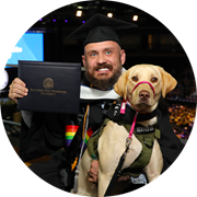 U.S. Army veteran, SNHU gradudate and Massachusetts resident Jereme West holding his service dog and SNHU diploma.