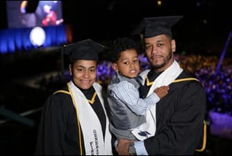 SNHU graduates Darian Beauchamp and Catherine Mosquea wearing their caps and gowns along with their young son at SNHU Commencement.