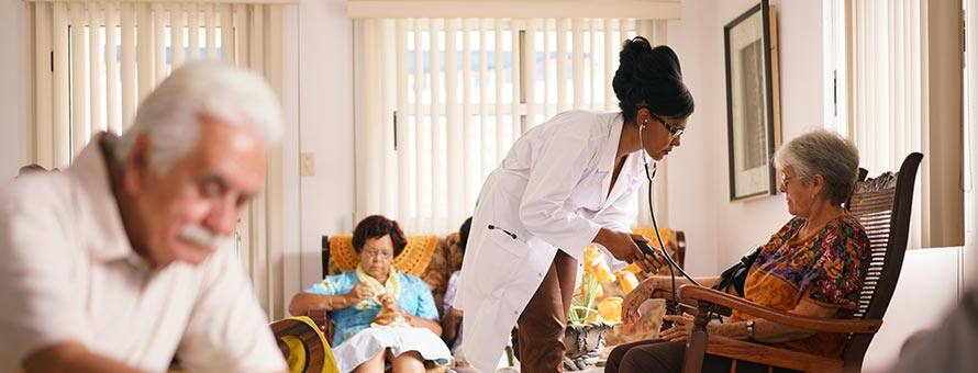 A healthcare professional checking the blood pressure of a woman in an assisted living facility.