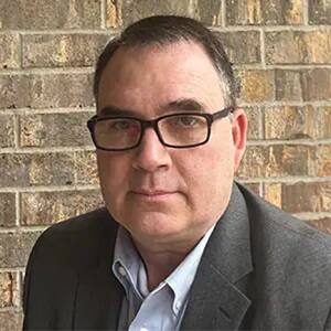 Ryan Whitaker, an adjunct faculty member in SNHU's online MS in management with a concentration in Construction Management program, in front of a brick wall.