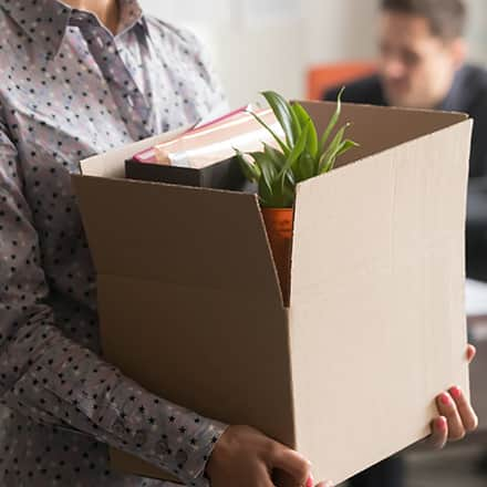 A person carrying a box as they leave their job