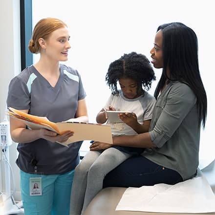 A nurse practitioner talking to a woman and her young daughter.