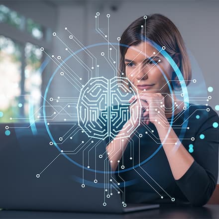 A person resting her chin on her folded hands, researching AI courses on a laptop.