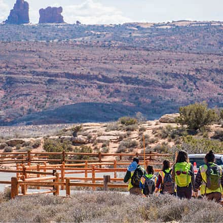 Women in yellow safety vests near a wooden railing in the Utah desert.