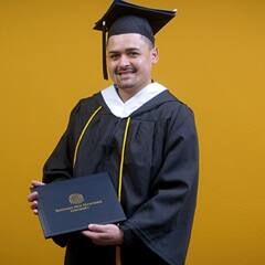 Anthony Fernandez, SNHU graduate with a bachelor's in political science holding his diploma.