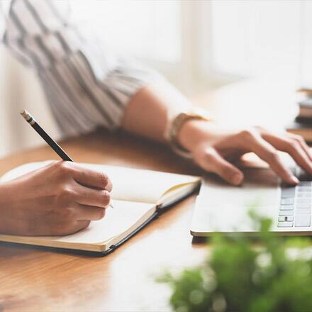 A person holding a pencil, taking notes on how to teach writing.