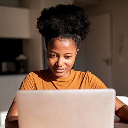 A student sitting at her desk working on her laptop researching Black History Month