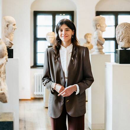 A historian standing in the middle of a room in a museum full of statues