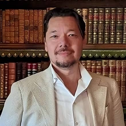 Dr. Christopher Lee, an associate dean of English programs at SNHU, standing in front of a bookcase. 