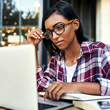 A person sitting by a window, researching certificate programs on a laptop.