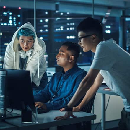 Three people in a computer lab working on a cybersecurity project.