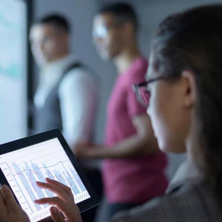 Data analyst looking at a tablet with data charts on it.