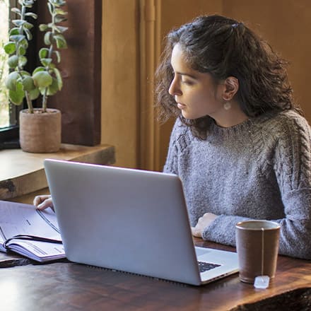 A person with a laptop and notebook, considering the difference between a bachelor's degree and a master's degree.