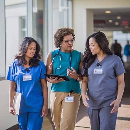 Three nurses at different career levels walking in a hospital corridor with the text types of nursing degrees.