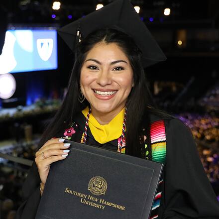 Eliana Cornejo holding her diploma at her SNHU commencement ceremony