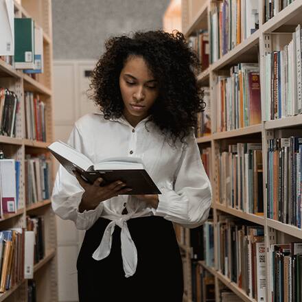 A woman with an English literature degree reading a book in a library