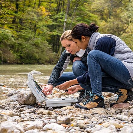 Two environmental science students working along the side of a river