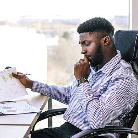 A man contemplates the difference between finance vs accounting, looking at a series of charts at his desk.