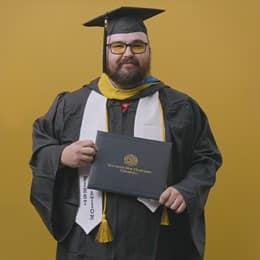 Frank Milisi, an SNHU graduate with a bachelor's in computer information systems, dressed in his graduation cap and gown.