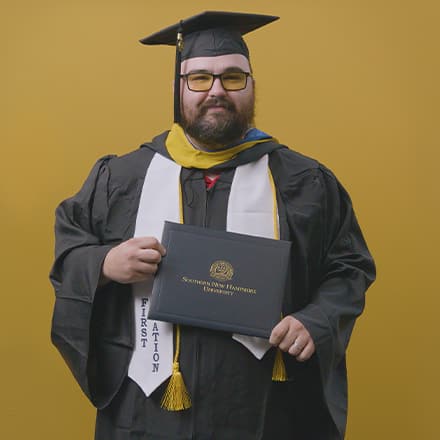 Frank Milisi, an SNHU graduate with a bachelor's in computer information systems, dressed in his graduation cap and gown.