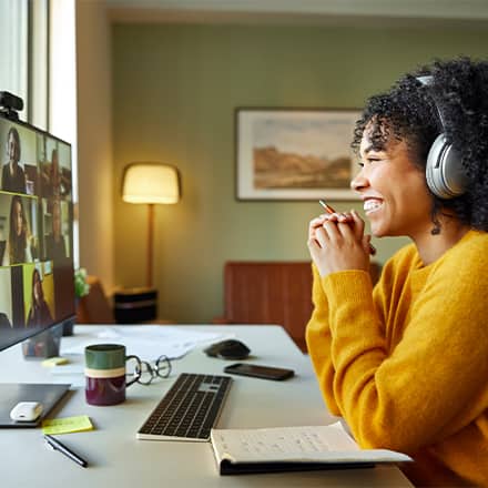 A woman working from home sitting at her desktop on a work video call.