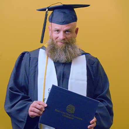Gerald Pruitt '25, operations management with a concentration in project management from SNHU, holding a diploma cover.