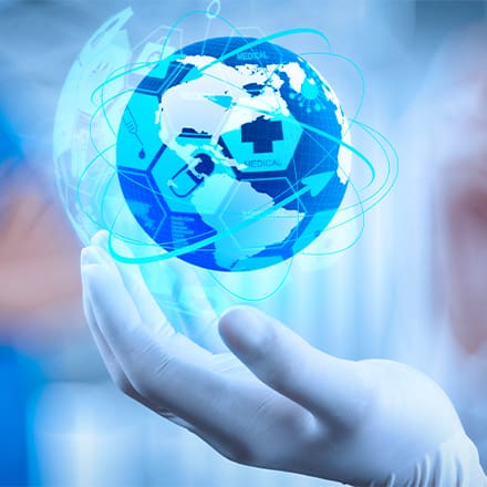 A gloved hand holding a glowing globe with medical icons and network lines, against a blue clinical background.