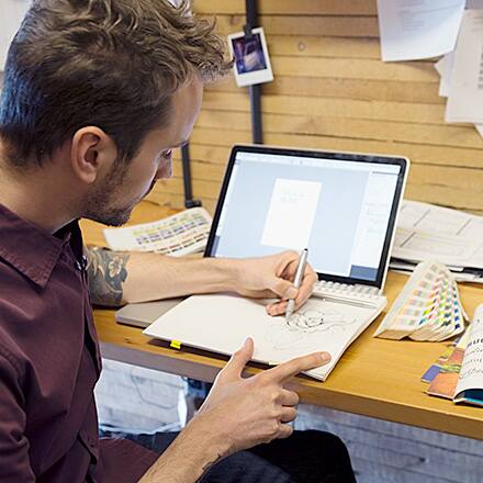 A man sits and creates a graphic design portfolio