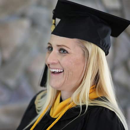 Kimberly Cartier smiling while wearing at cap and gown