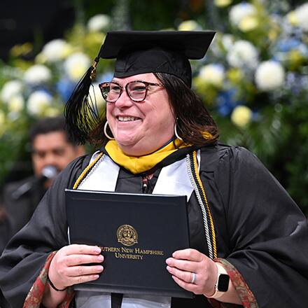 An SNHU graduate at Commencement earning their degree.