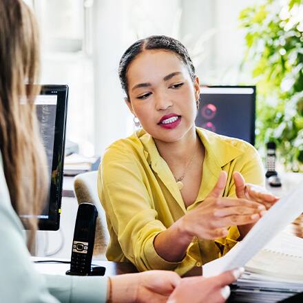 An employee holding her resume and listening to her mentor tell her how to become a manager