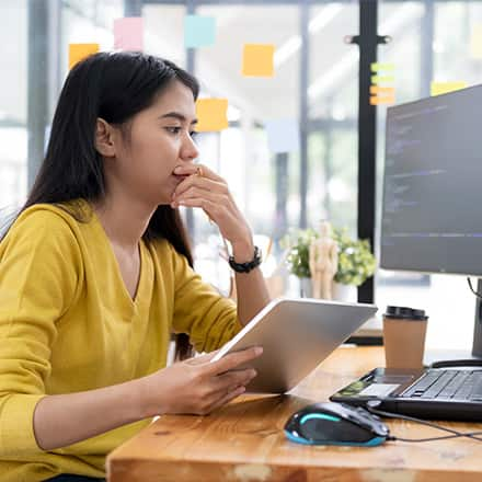 A woman looks at a computer screen studying how to become a software engineer