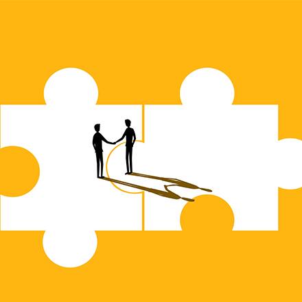 Two silhouettes shaking hands on puzzle pieces to represent negotiation.