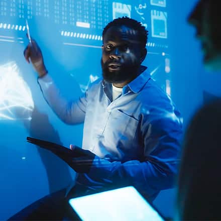 A tech professional presenting data projected in blue.