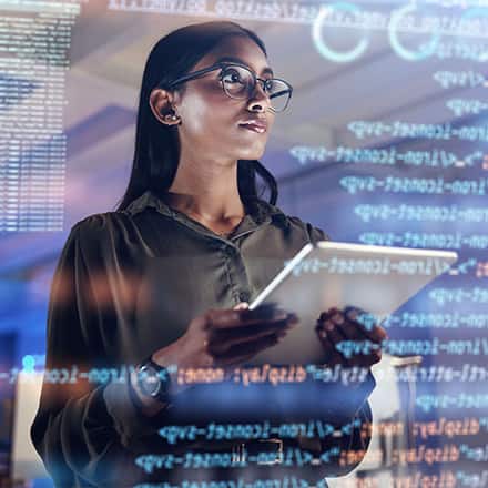 A woman wearing glasses and working on cybersecurity project on a tablet.