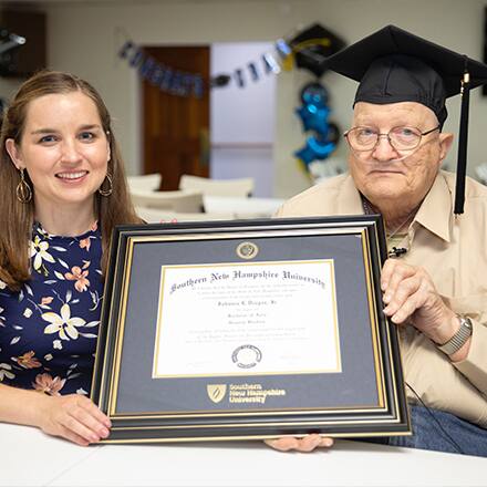 SNHU graduate John Draper holding his diploma with his advisor Courtney Hannon