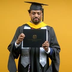 Josiah Lee, a 2025 master's in cybersecurity graduate from SNHU, wearing a cap and gown and holding his diploma.