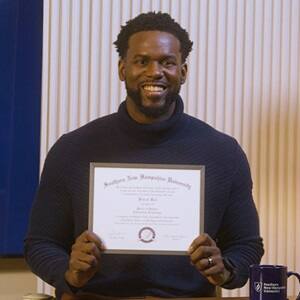 Kitrick Bell, a 2025 SNHU graduate who earned his master's in information technology with a concentration in software application development, smiling and holding his diploma.
