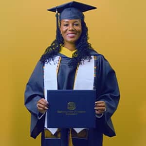 Kyla Johnson-Curtis, a 2025 SNHU grad who earn her bachelor's in operations management with a concentration in logistics and transportation holding her diploma in front of a yellow background.
